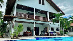 A two-story house with a balcony, a swimming pool, and tropical plants. - Lyndale Lodge (Sam Roi Yot)