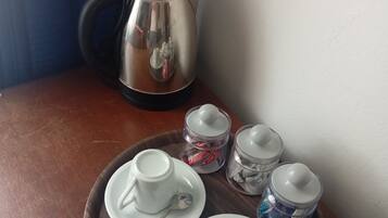 Un safataire amb dues tasses i platets blancs, una cullera i dos recipients de vidre amb tapa sobre una taula de fusta.
