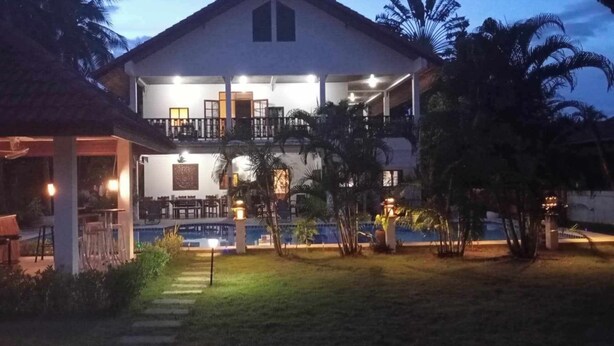 A two-story building with a balcony, a pool, and a covered outdoor seating area. - Lyndale Lodge (Sam Roi Yot)