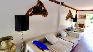 A living room with a beige sofa, decorative wall art, a black floor lamp, and a brass vase. - Lyndale Lodge (Sam Roi Yot)