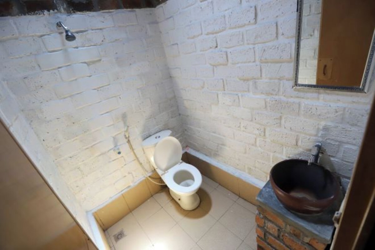 A bathroom with a white toilet, a shower area, and a sink with a brown basin.