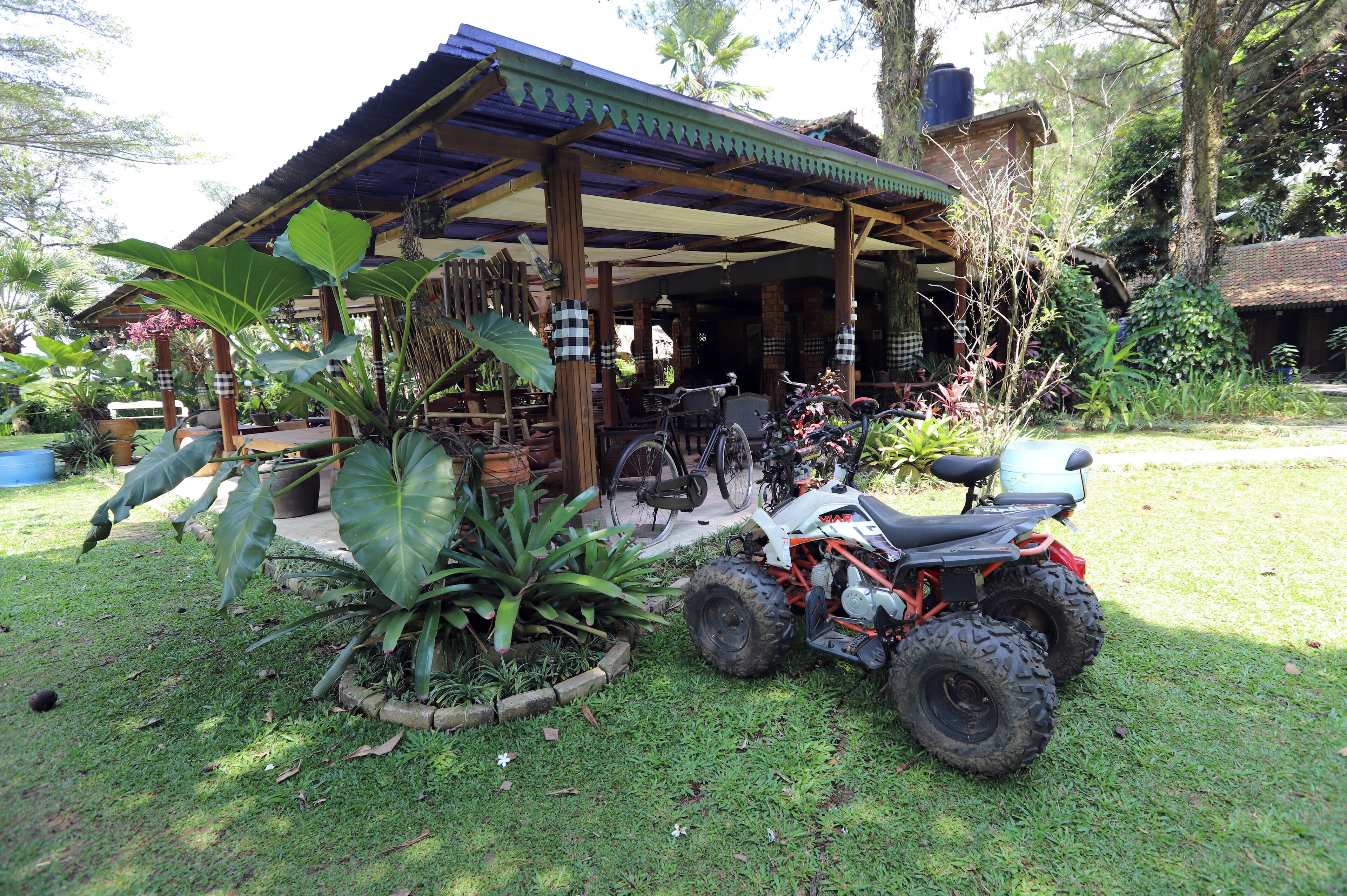 A covered outdoor seating area with a bicycle and an ATV parked nearby.