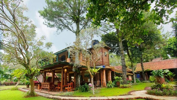 Un bâtiment de style rustique doté d’un patio couvert, entouré d’une végétation luxuriante et d’une pelouse bien entretenue.