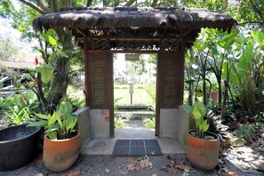 Une construction traditionnelle avec un toit de chaume, entourée de plantes en pot et d’un petit jardin.