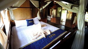 Un lit à baldaquin, une couvre-lit bleue et dorée, et un oreiller orné de l’inscription « ARBA Hospitality ».