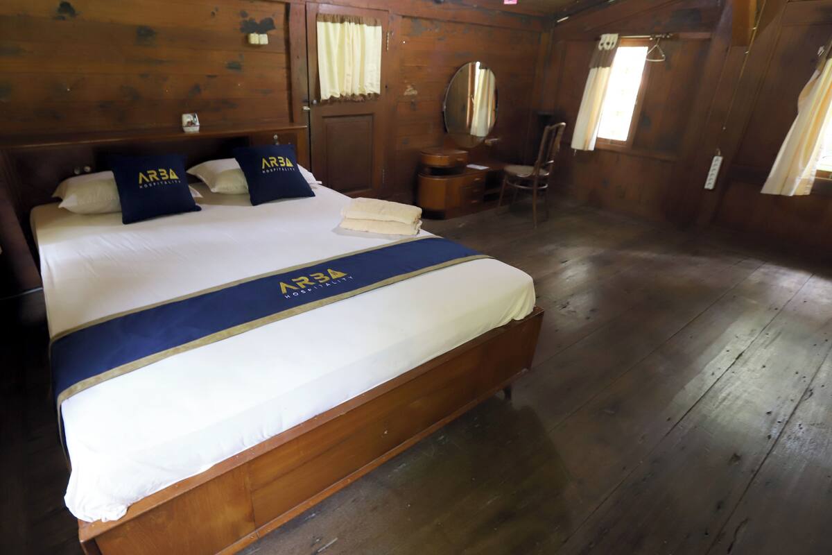 A wooden room with a large bed, a wooden desk, and a chair.