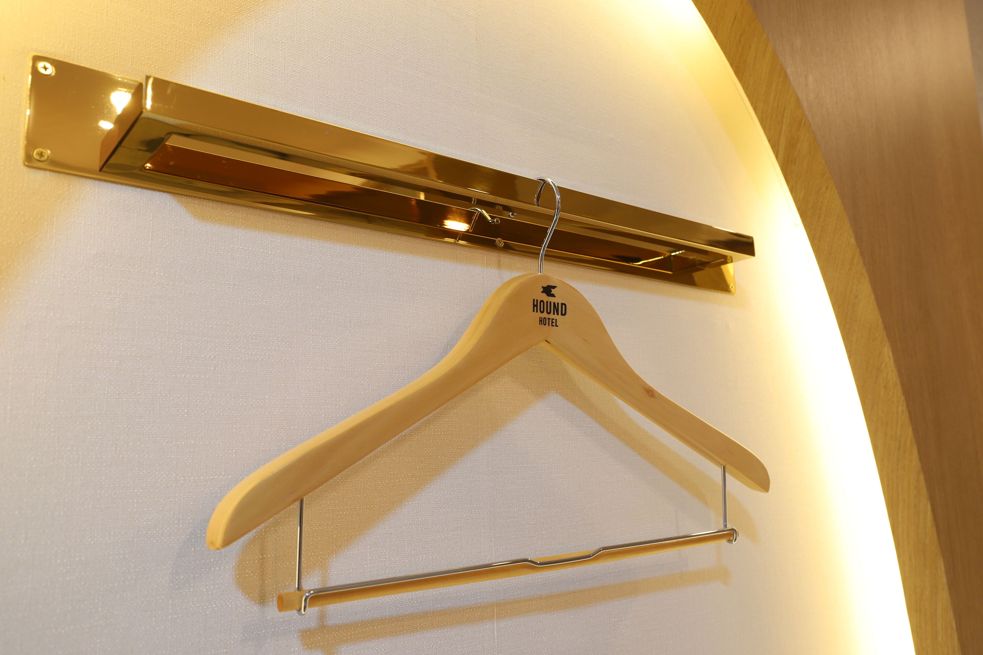 A wooden hanger with a label hanging on a wall-mounted metal rack.