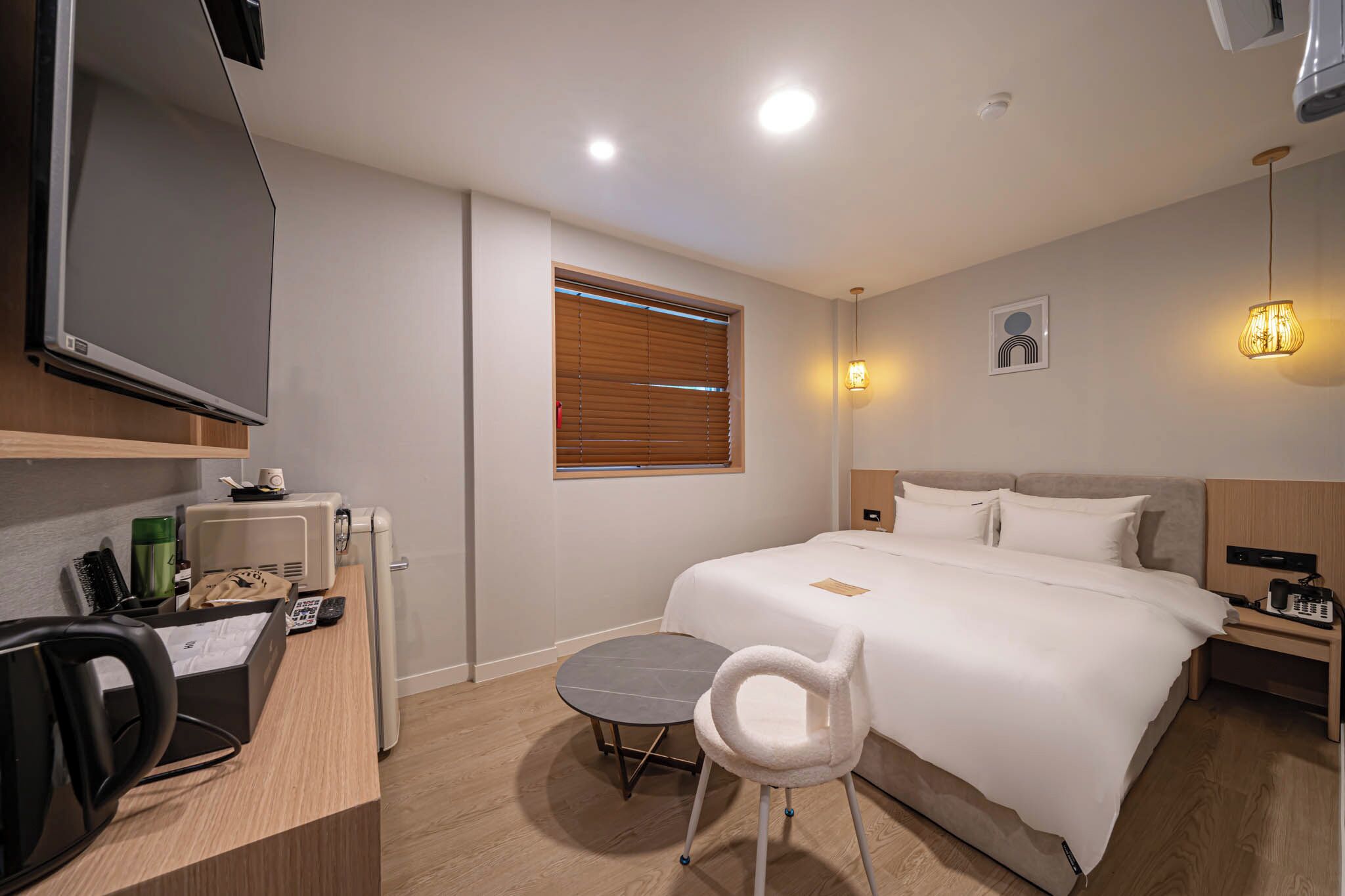 Une chambre d’hôtel comprenant un lit, une table de chevet, un bureau, une chaise et un téléviseur.