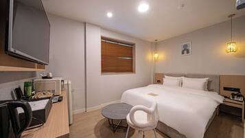 Una habitación de hotel con cama, mesita de noche, escritorio, silla y televisión.