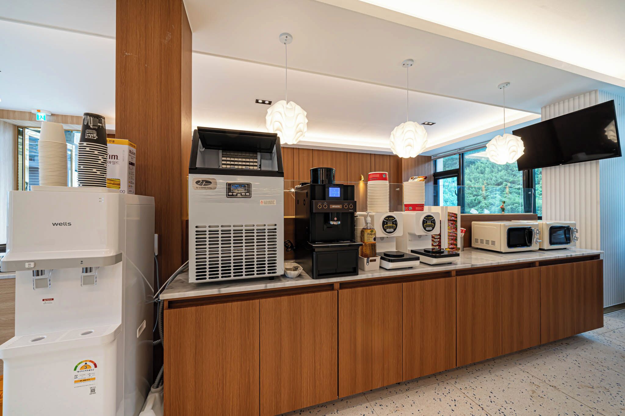 A modern kitchen area with a coffee machine, microwave, and water dispenser.