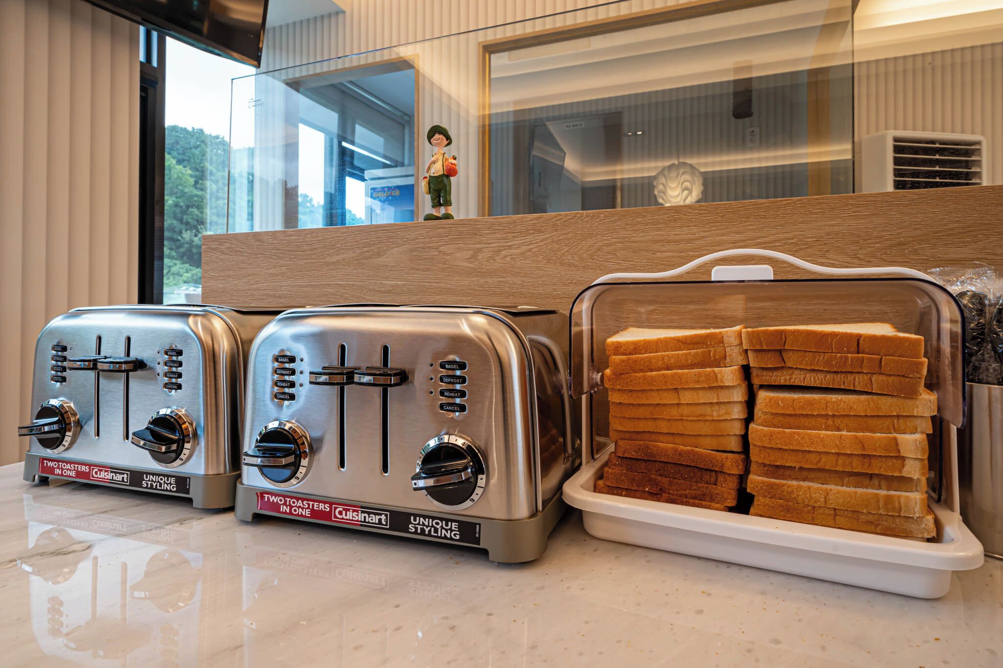 Two Cuisinart toasters on a countertop with a tray of sliced bread.