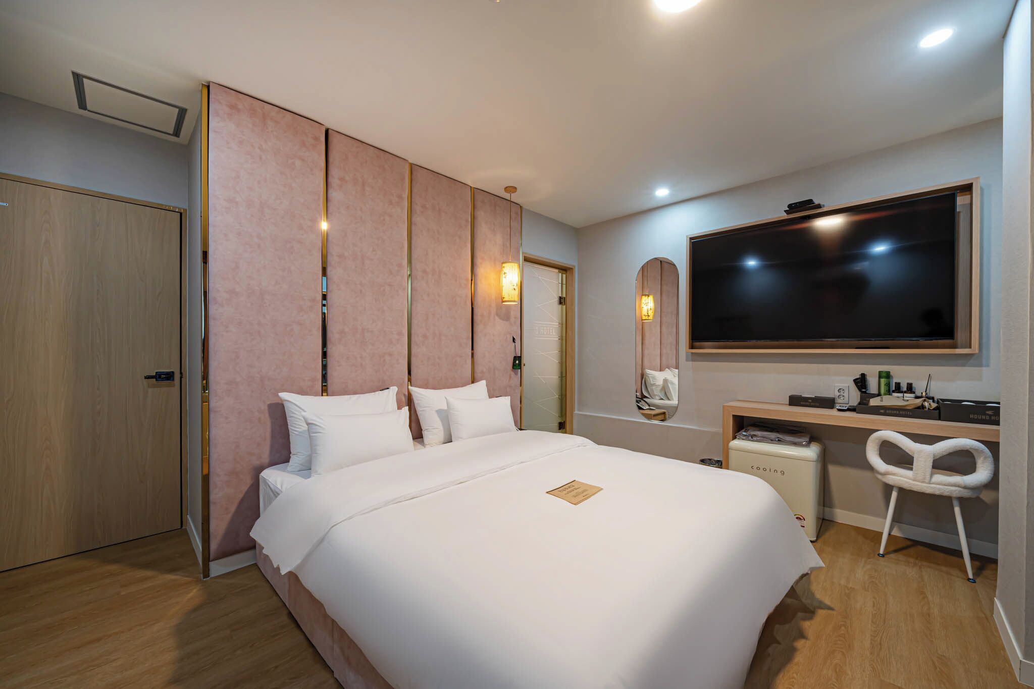 A hotel room with a large bed, a desk with a chair, a television, and a minibar.