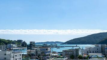 A coastal cityscape with buildings, a harbor, and a mountainous backdrop.