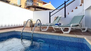 A swimming pool with two sun loungers and a metal ladder.