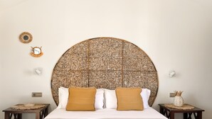 A neatly made bed with two pillows, a woven headboard, and two nightstands with decorative items.