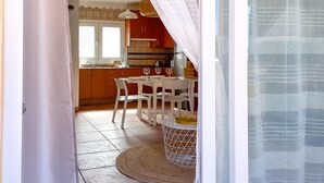 A kitchen with a dining area, featuring a table with chairs, a round rug, and a hanging light fixture.