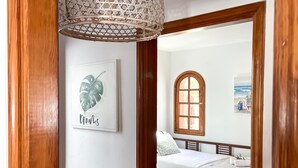A bedroom with a bed, a window, and a wall-mounted artwork.