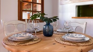 A dining table set with plates, glasses, and a blue vase with a plant.