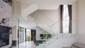 Een moderne woonkamer met een glazen trap, een bank en een marmeren open haard.