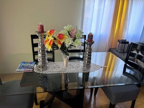 Enjoy meals in this stylish dining area with a glass table, lace centerpiece, and comfortable seating.