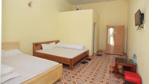 A room with two beds, a wooden wardrobe, a small table, a fan, and a television. - Viet Hoang Hostel Moc Chau - BAYLUXURY (Thao Nguyen)