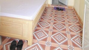 A bedroom with a bed, a door leading to a bathroom, a ceiling fan, and patterned floor tiles. - Viet Hoang Hostel Moc Chau - BAYLUXURY (Thao Nguyen)