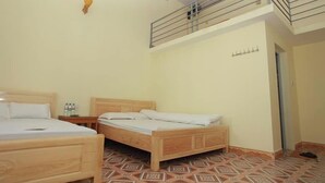 A room with two wooden beds, a small table with a bottle, and a patterned floor. - Viet Hoang Hostel Moc Chau - BAYLUXURY (Thao Nguyen)