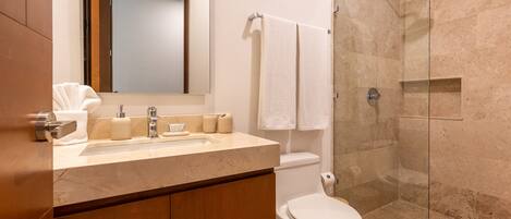 A modern bathroom with a marble sink, a toilet, a glass-enclosed shower, and a wooden vanity.