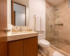Ein modernes Badezimmer mit Marmorwaschbecken, Toilette, Duschkabine aus Glas und einem Holzkorpus.