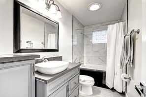 Een moderne badkamer met een grote spiegel, een wastafel, een toilet en een douche.