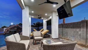 An outdoor patio area with wicker furniture, a pool, and a waterfall feature. - ScottsdaleStays Grand Chateau - 12BR Resort Estate - 500K Pool + Courts (Phoenix)