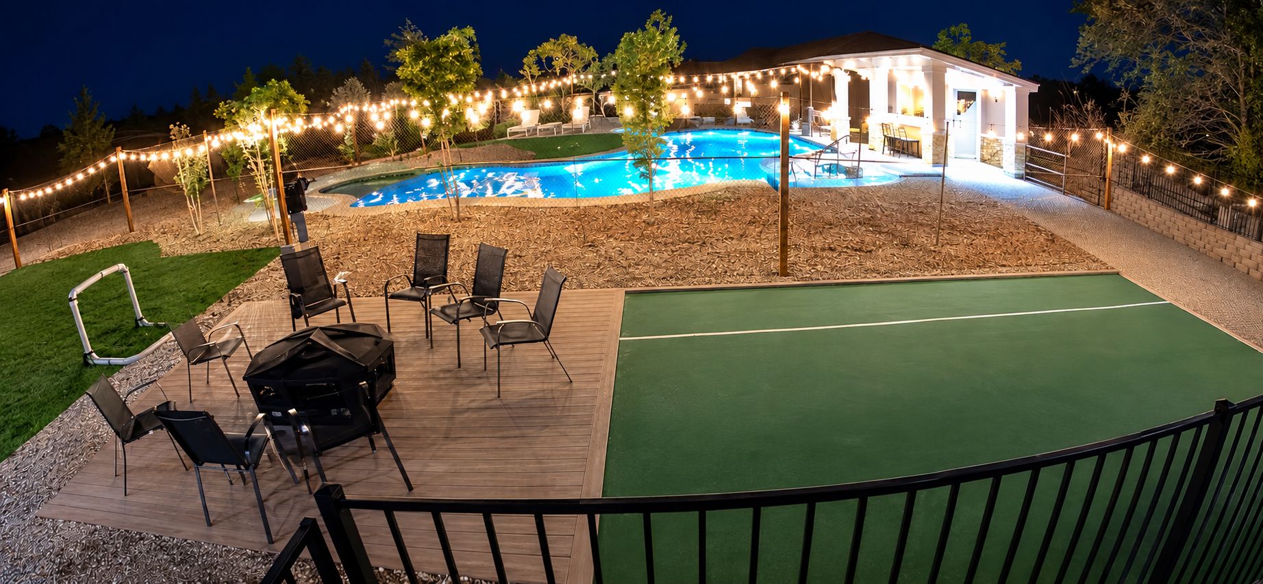 A backyard with a swimming pool, deck chairs, and a covered patio area.