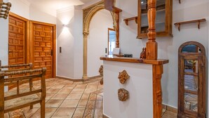 A hallway with wooden doors, a bench, a mirror, and a decorative column. - Amazing home in Algarinejo (Algarinejo)