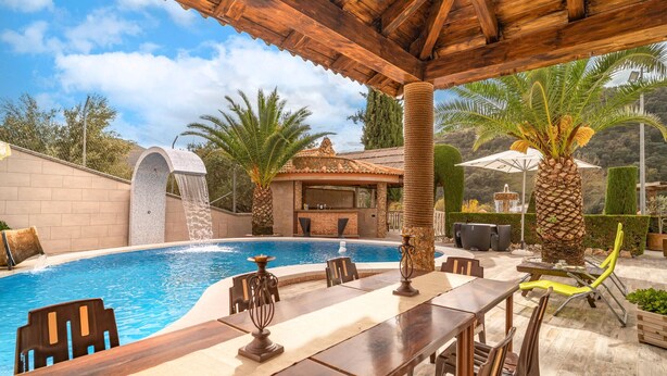 A pool with a waterfall feature, a covered bar area, and outdoor seating. - Amazing home in Algarinejo (Algarinejo)