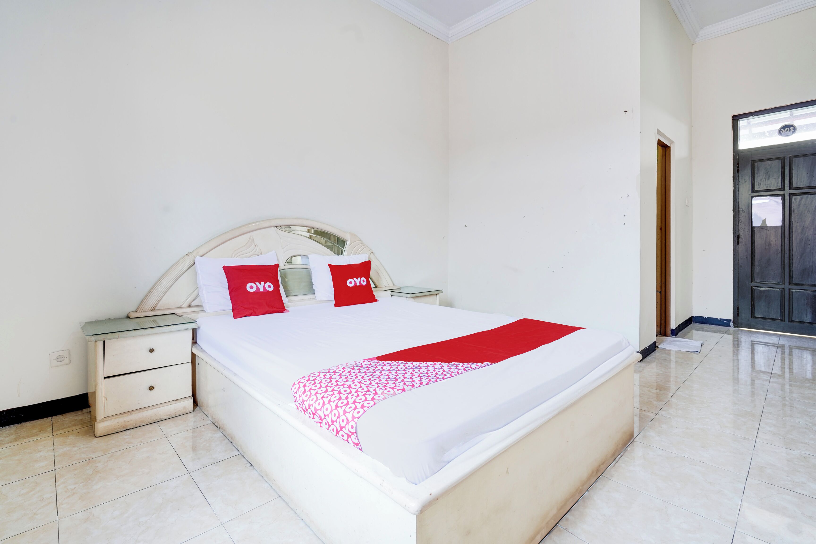 A neatly made bed with a white and red bedspread, two matching pillows, and a wooden headboard.