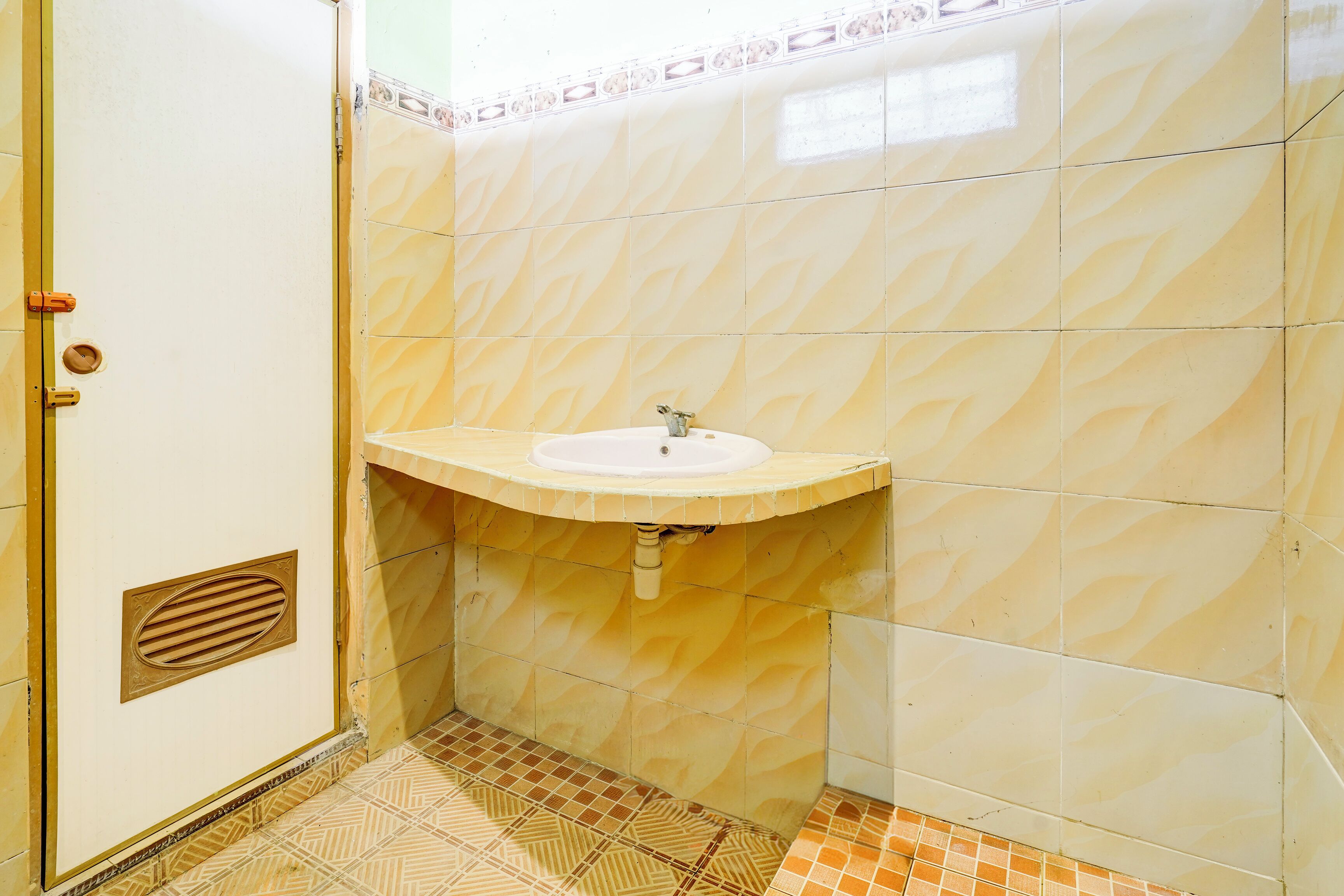 Un baño con lavamanos, paredes de azulejos y suelo estampado.