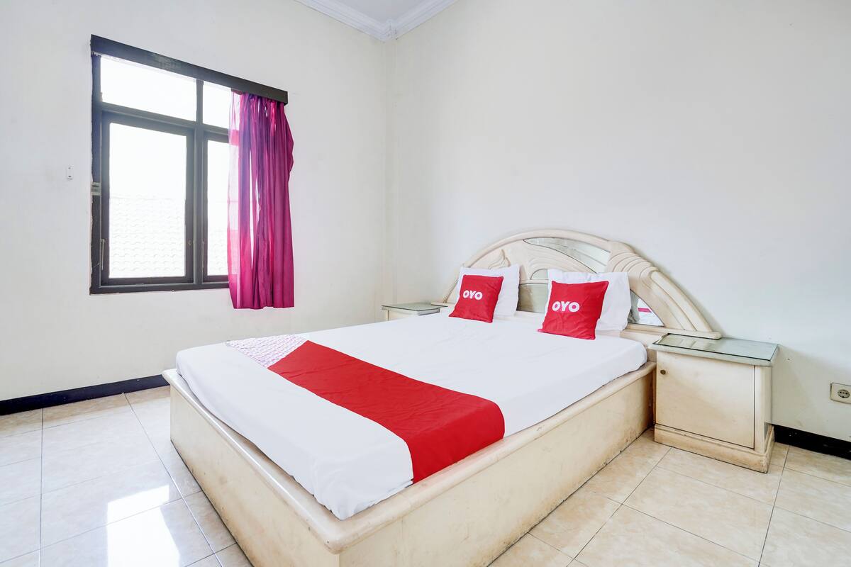 A neatly arranged hotel room with a bed, a nightstand, and a window with curtains.