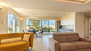 A modern living room with a sofa and a coffee table, a dining area with chairs and a table, and a kitchen with cabinets and appliances. - Incoronata New Dependance by Interhome (Gallipoli)