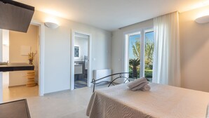 A modern bedroom with a large bed, a desk, and a view of the outdoors through a sliding door. - Incoronata New Dependance by Interhome (Gallipoli)