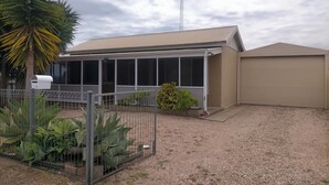 Un bâtiment doté d’un patio couvert, d’un jardin clos avec de grandes plantes et d’un garage.