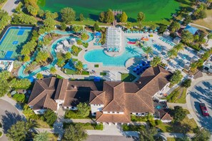 An aerial view of a resort with multiple swimming pools, a tennis court, and a variety of outdoor seating areas.