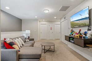 Una sala de estar con un sofá, una mesa de centro y un televisor montado en la pared.