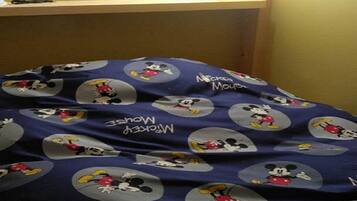 Uma cama com uma colcha decorada com o tema do Mickey Mouse.