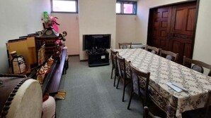 Een eethoek met een lange tafel, stoelen, een televisie en een open haard.