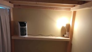 Een stapelbed met een verwarming en een lamp op een plank erboven.