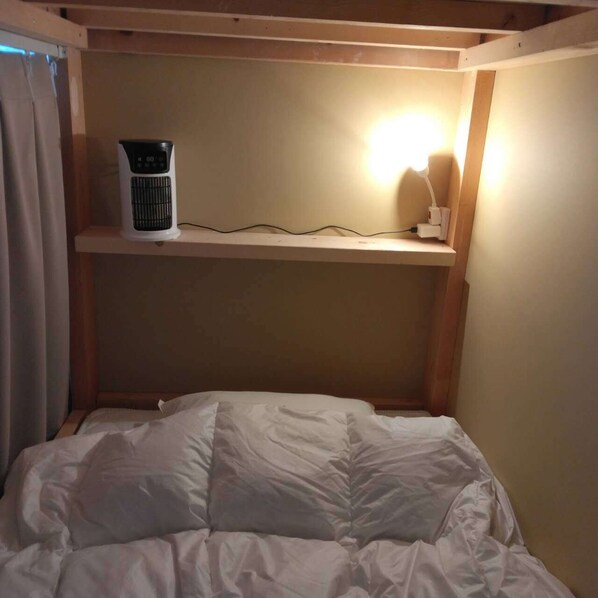 Una cama litera con un calentador y una lámpara sobre una repisa.