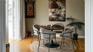 En matplats med ett runt bord, fyra stolar, en vävd matta och en stor tavla med ett lejonmotiv på väggen.
