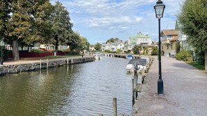 En kanal med båtar, en stenmur och hus längs vattnet.