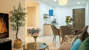Una sala de estar moderna con un sofá, sillas, una mesa de centro, un televisor, una chimenea y una zona de comedor con una mesa y sillas.