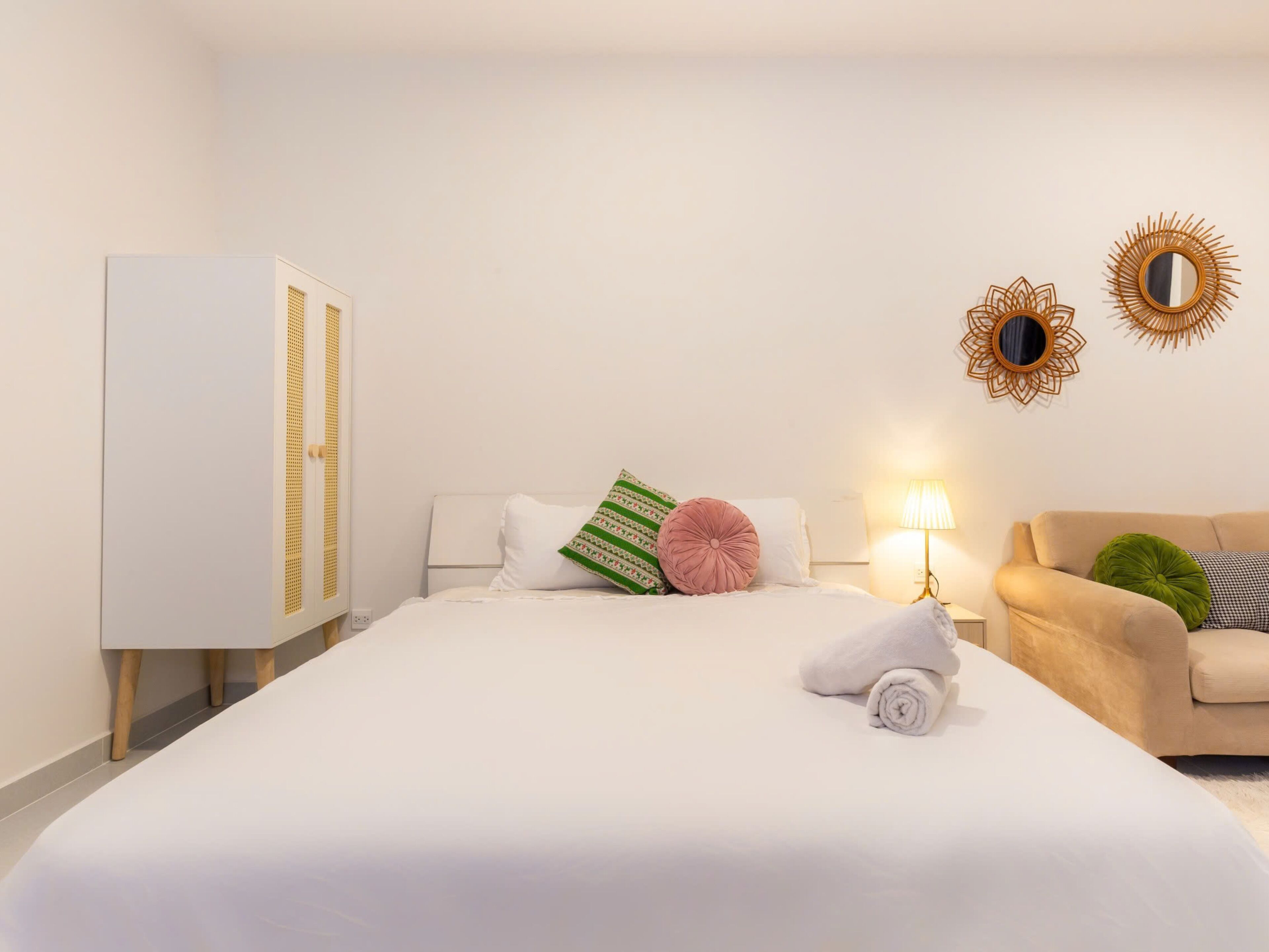 Una habitación de hotel con una cama grande, un sofá, una lámpara y dos adornos en la pared.